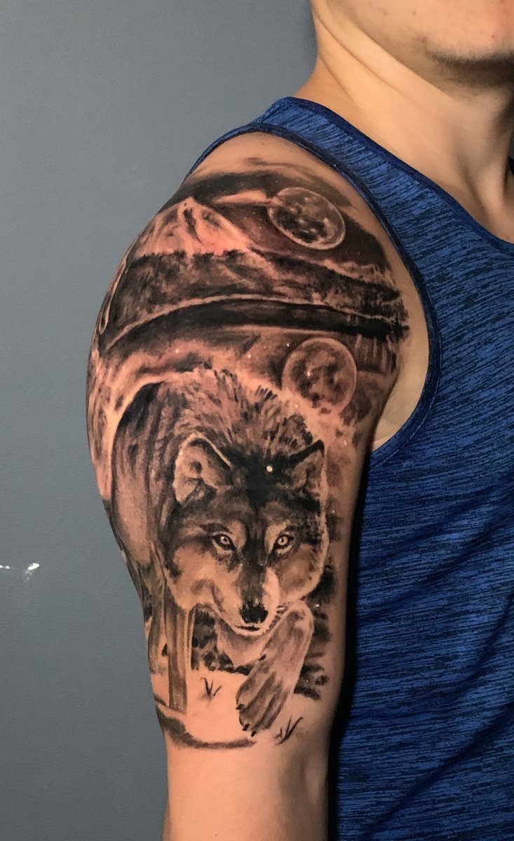 Black and gray realism wolf upper arm half sleeve tattoo with mountain and full moon landscape by Zack Ross, tattoo artist Kyle TX near Austin